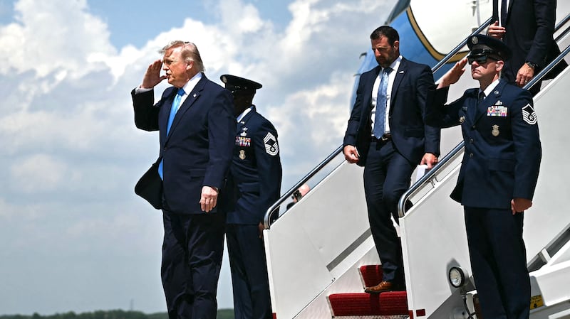 US President Donald Trump, trailed by Secretary of Homeland Security Markwayne Mullin, salutes as he exits Air Force One