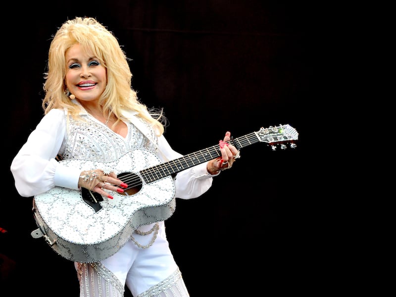 Dolly Parton plays a bedazzled guitar.