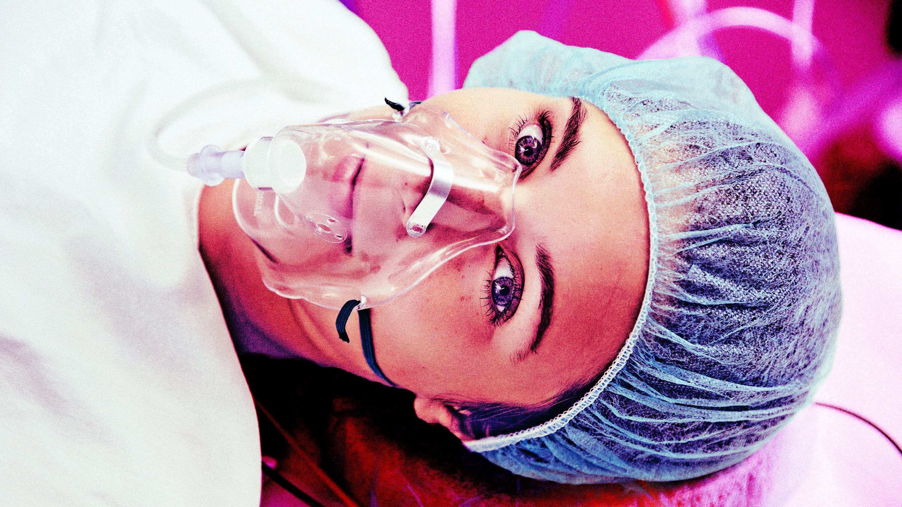 A photo illustration of a patient with respiratory mask awake on operating room table.