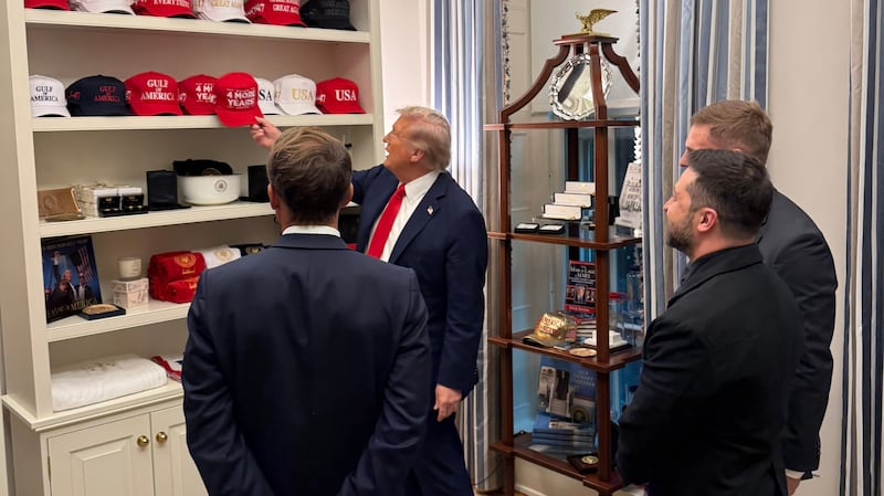 Trump shows Zelensky and Macron his trolling MAGA hat collection at Ukraine White House summit.