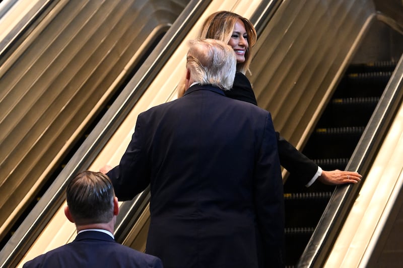 Melania appears to smile after someone yells at Trump, "Be careful with the stairs!"