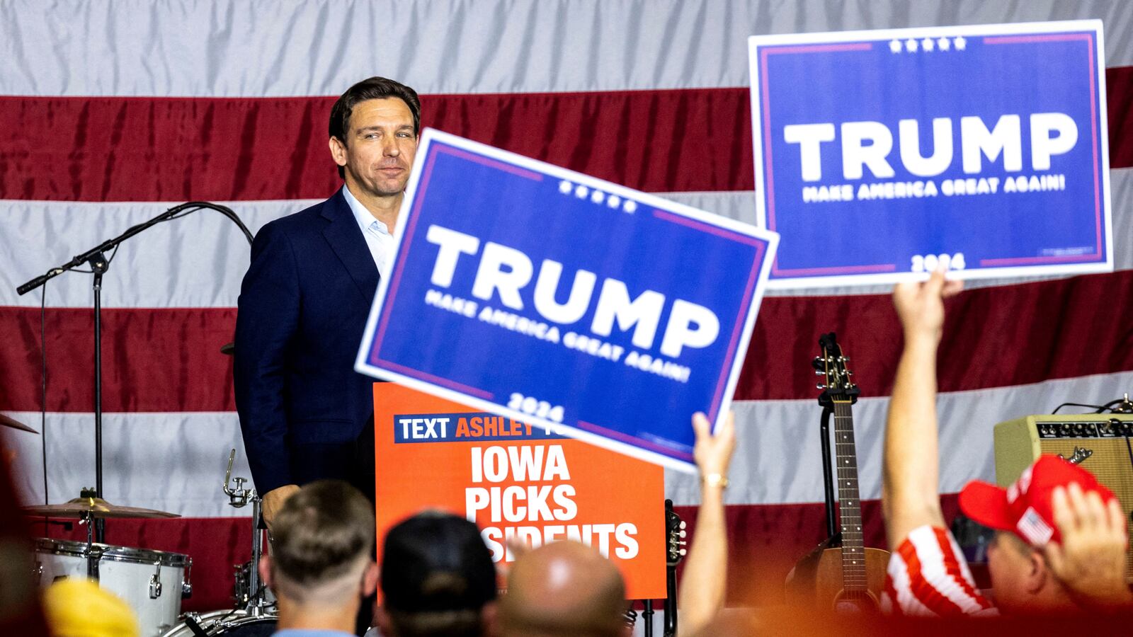 Republican U.S. presidential candidate and Florida Governor Ron DeSantis looks into the crowd after speaking as supporters of former President Donald Trump hold up signs.