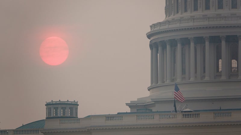 The sun rises behind the U.S. Capitol building during a summer heat wave as smoke from wildfires in Canada fills the air