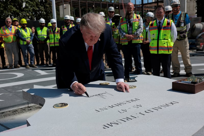 President Donald Trump signs a stone that will be inserted into the helipad that is being constructed on the South Lawn, at the White House in Washington, D.C., U.S., August 19, 2026.