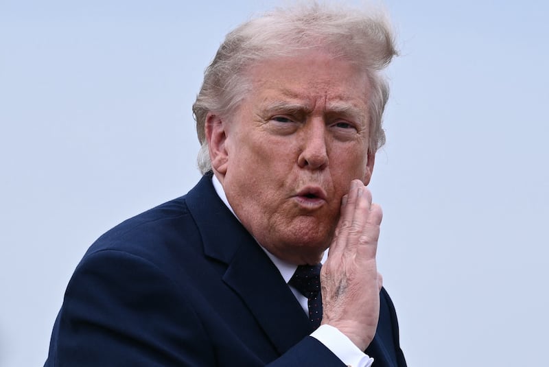 Trump shows his bruised hand while gesturing to reporters on his way to Air Force One.