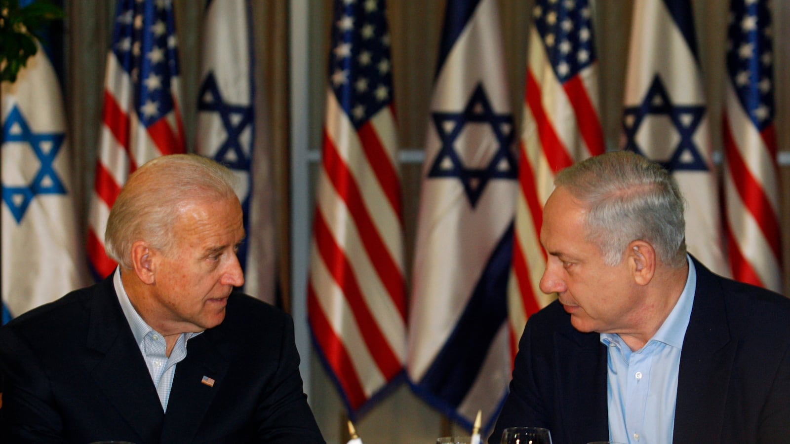 Then-U.S. Vice President Joe Biden sits with Israel's Prime Minister Benjamin Netanyahu before flags