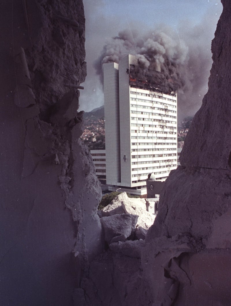 The parliament building, seen from the destroyed interior of a downtown hotel, burns after being hit with an artillery shell fired from Serb positions on the hills surrounding Sarajevo on August 20, 1992.   REUTERS/Corinne Dufka
