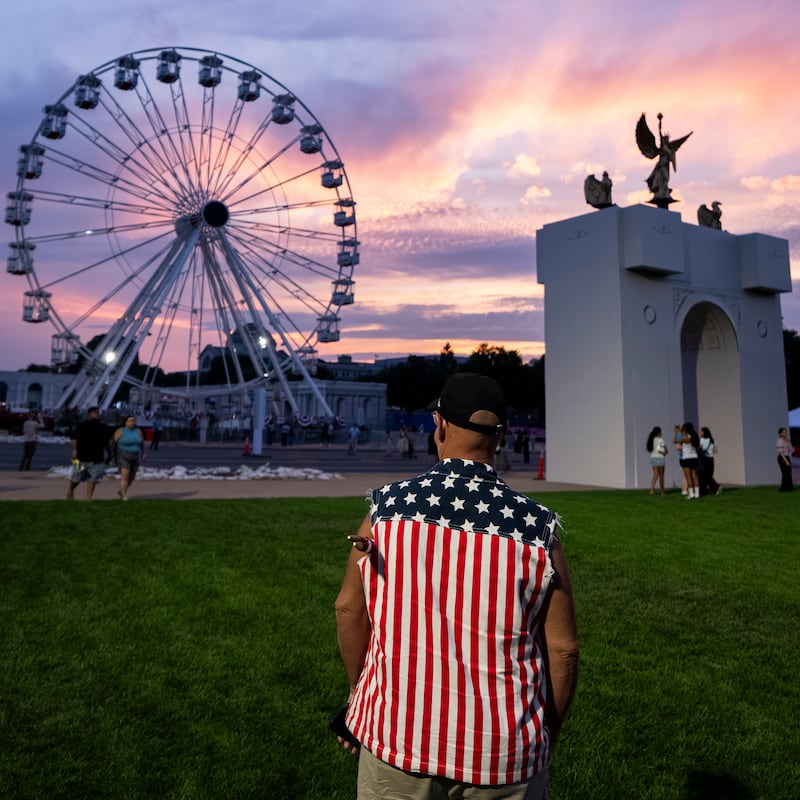 The sun sets behind a replica of the planned Triumphal Arch and the 110-foot "Freedom 250" ferris wheel on the first day of the Great American State Fair on the National Mall.