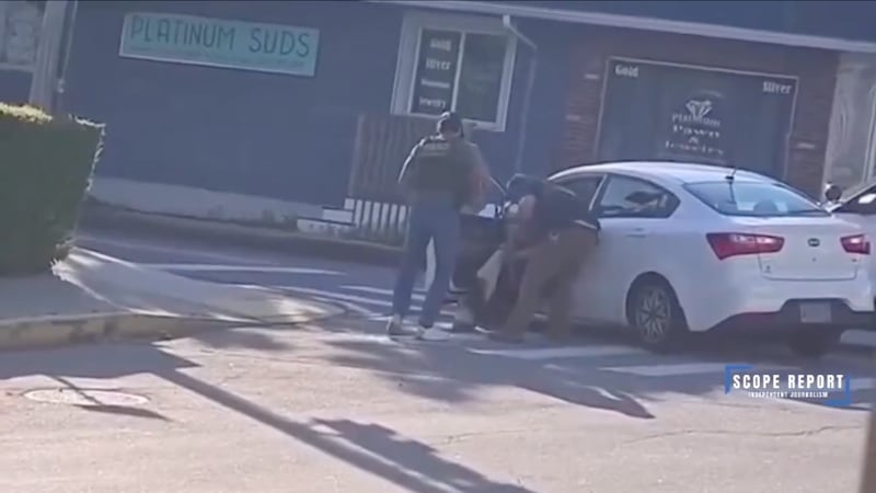 Two men in ICE vests drag a man out of a white Kia Ceed