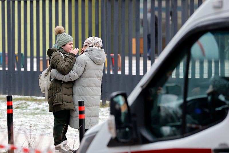 Relatives of a killed child cry outside a school in Gorki-2, a village west of Moscow in the Odintsovo district, following a stabbing incident on December 16, 2025. A 10-year-old was stabbed to death at a school in Russia by an older pupil on December 16, 2025, the authorities said, adding that a suspect had been detained.