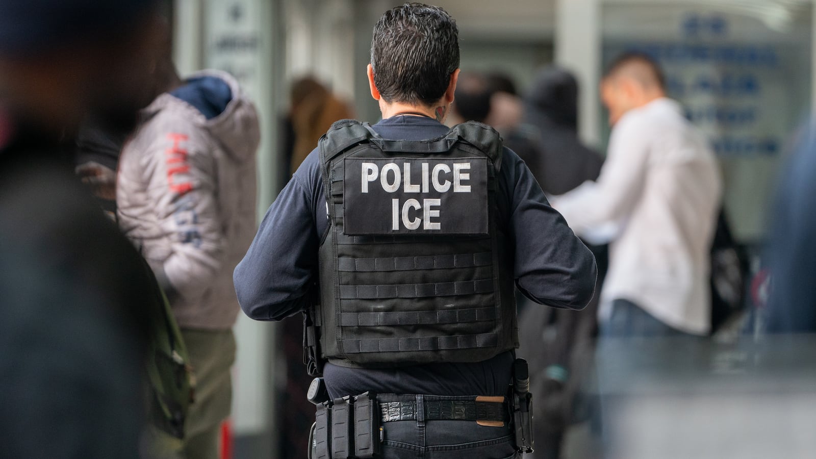 An ICE agent monitors hundreds of asylum seekers being processed upon entering the Jacob K. Javits Federal Building on June 6, 2023 in New York City.
