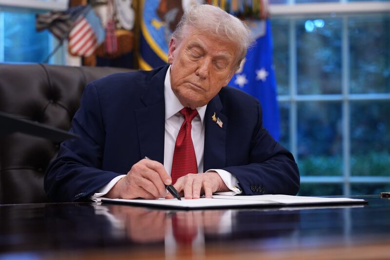 President Donald Trump holds signs an executive order in the Oval Office of the White House on September 25, 2025 in Washington, DC.