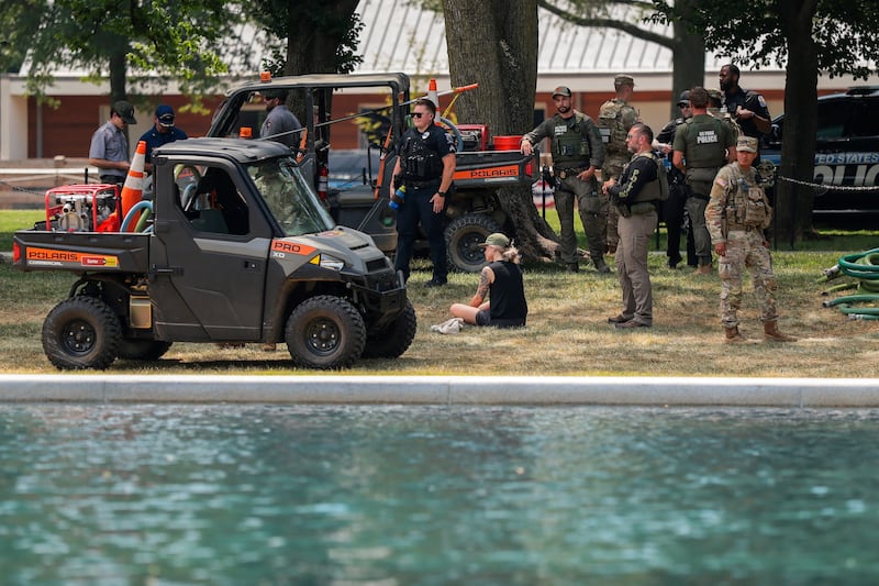 U.S. Park Police, members of the National Guard, and other officers stand around a person who allegedly took a piece of paint from the Lincoln Memorial Reflecting Pool, after recent renovations following a directive from U.S. President Donald Trump to paint it blue ahead of the 250th anniversary of U.S. independence, in Washington, D.C., U.S., June 22, 2026.