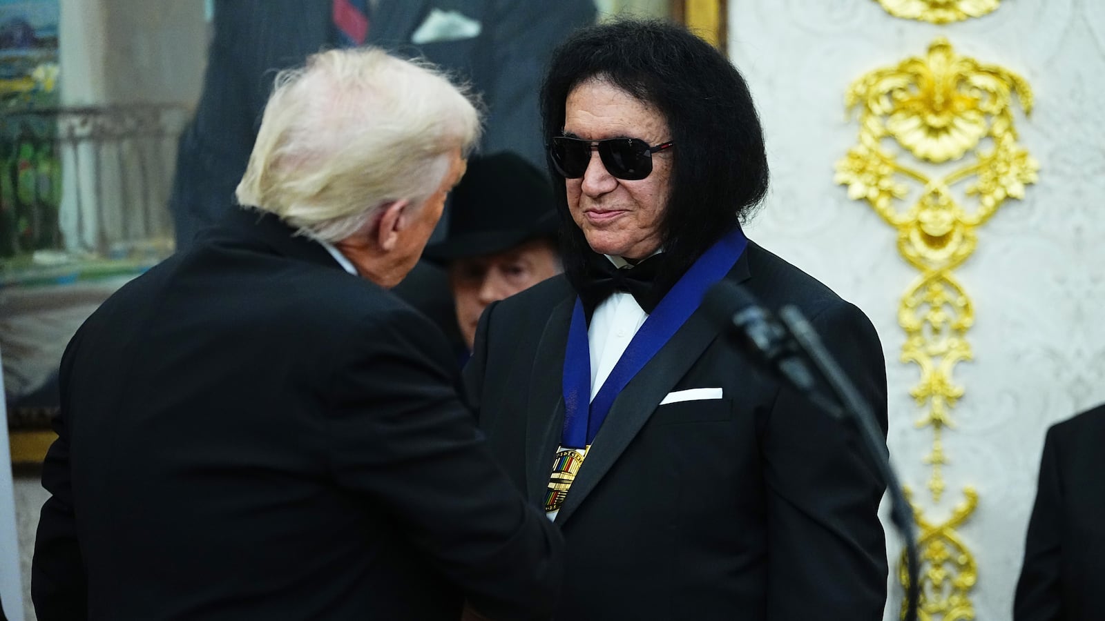 WASHINGTON, DC - DECEMBER 06: U.S. President Donald Trump (L) presents musician Gene Simmons (R) of the rock band KISS a medal for the 2025 Kennedy Center Honorees during a medal presentation in the Oval Office of the White House on December 06, 2025 in Washington, DC. The 2025 Kennedy Center honorees are Sylvester Stallone, George Strait, the rock band KISS, Gloria Gaynor, and Michael Crawford. (Photo by Aaron Schwartz/Getty Images)