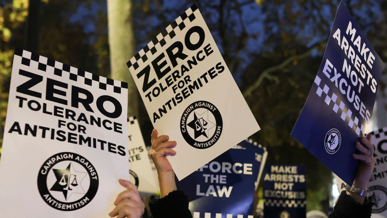 Demonstrators in the UK hold signs to condemn antisemitic crimes.