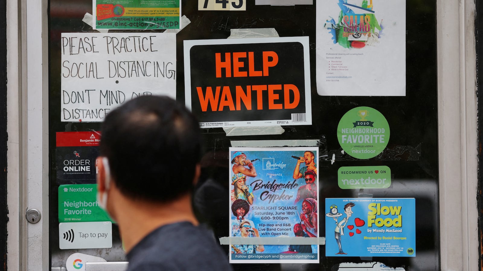 A man passes a “Help Wanted” sign on the door of a hardware store in Cambridge, Massachusetts.