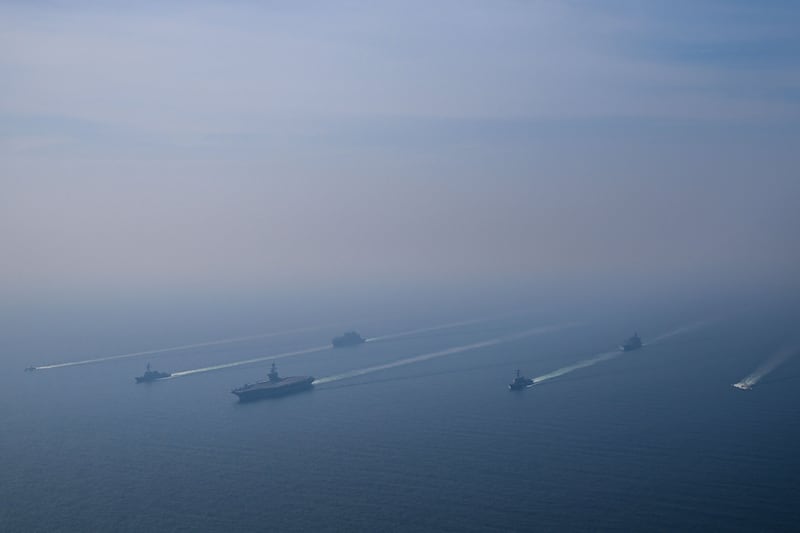 An aerial view of the USS Abraham Lincoln Carrier Strike Group while operating at the Arabian Sea, escorted by two military replenishment ships and two U.S. Coast Guard vessels, as fighter jets from Carrier Air Wing Nine conducted flight operations overhead in the Arabian Sea, on February 6, 2026.