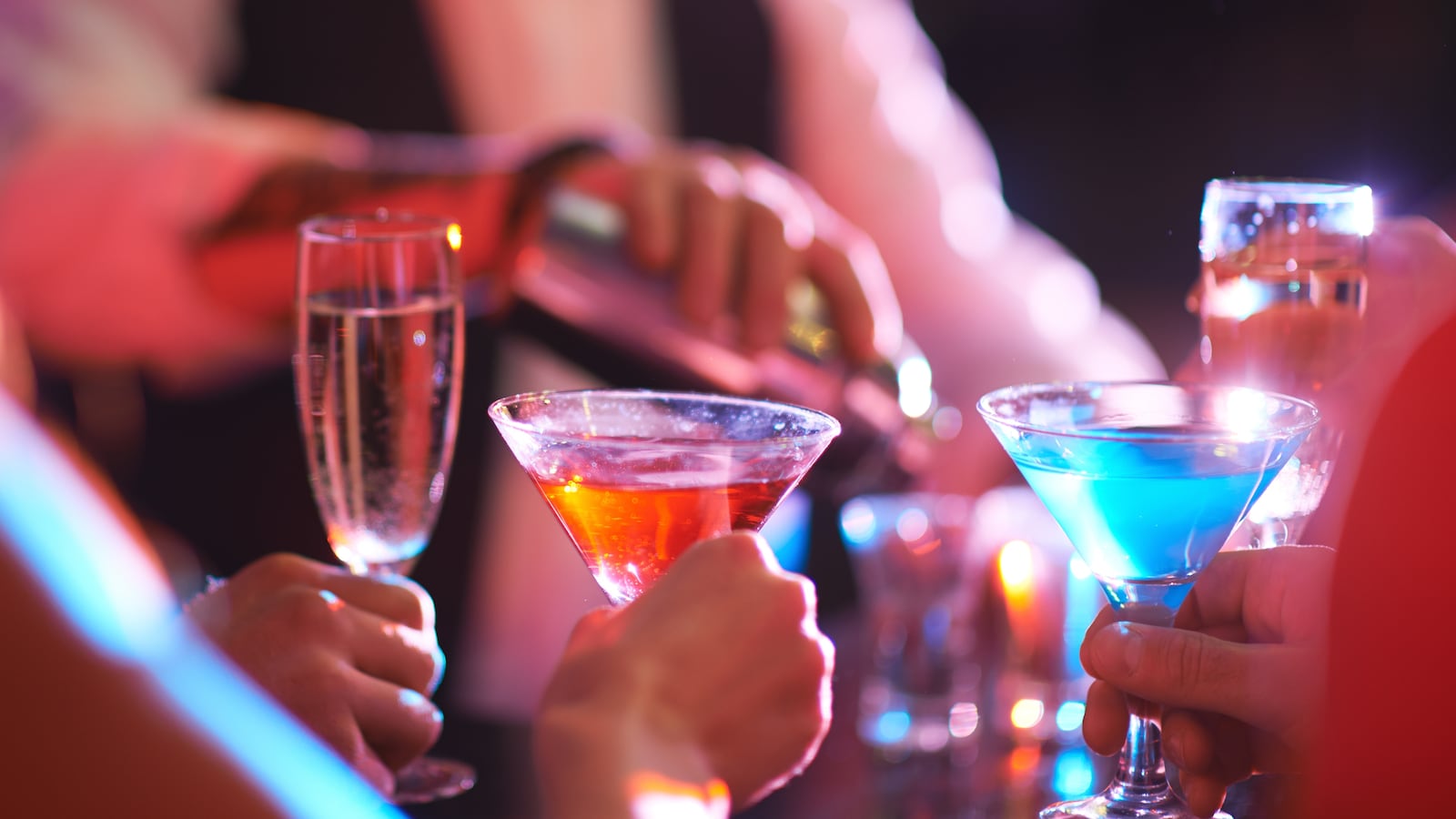 A group of people holding cocktails and champagne glasses in a bar.